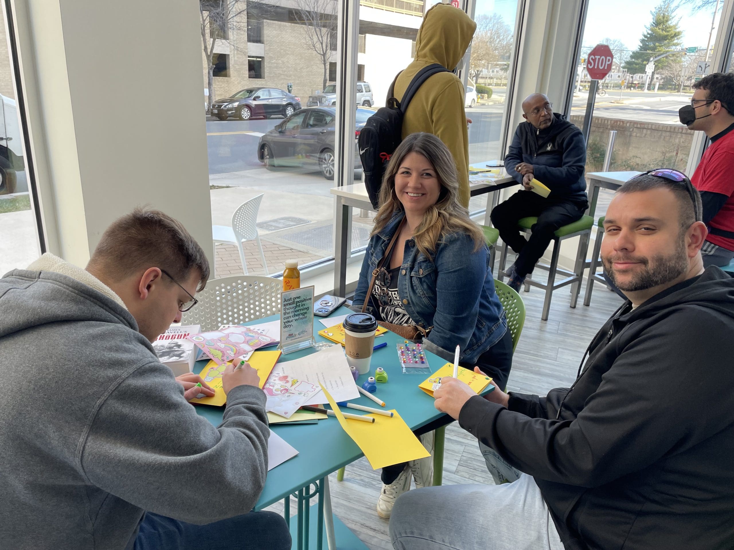 Three people making cards at a table in Soulfull Cafe