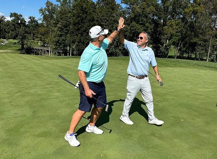 Two golfers high fiving at Main Street's 2023 Golf Outing