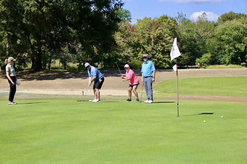 Foursome of golfers on the green of a hole at the 2023 Main Street Golf Outing