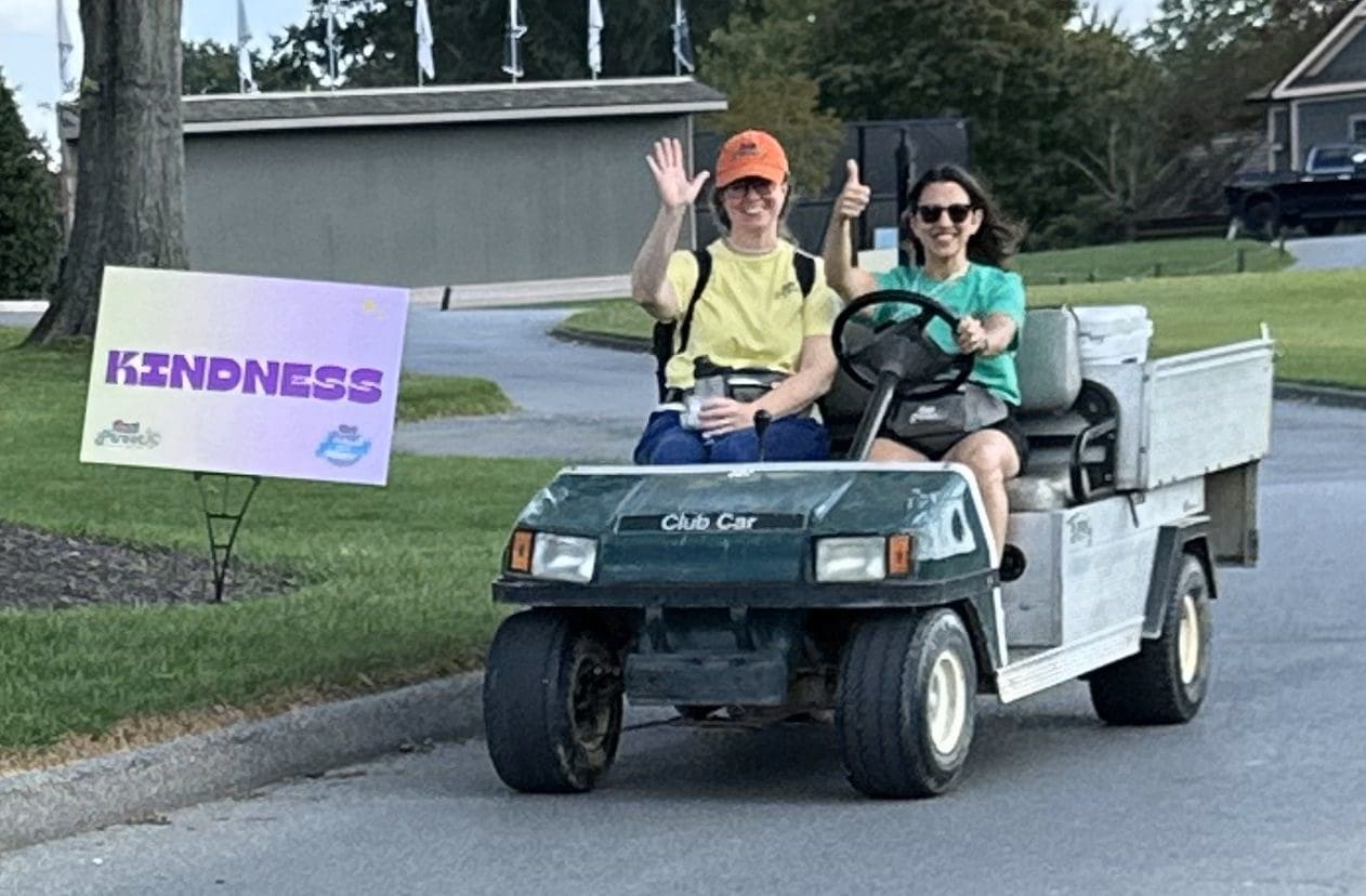 Main Street staff in golf cart with kindness sign at 2023 Main Street Golf Outing