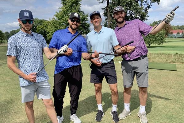 Foursome holding their clubs like guitars at Main Street's 2024 Golf Outing